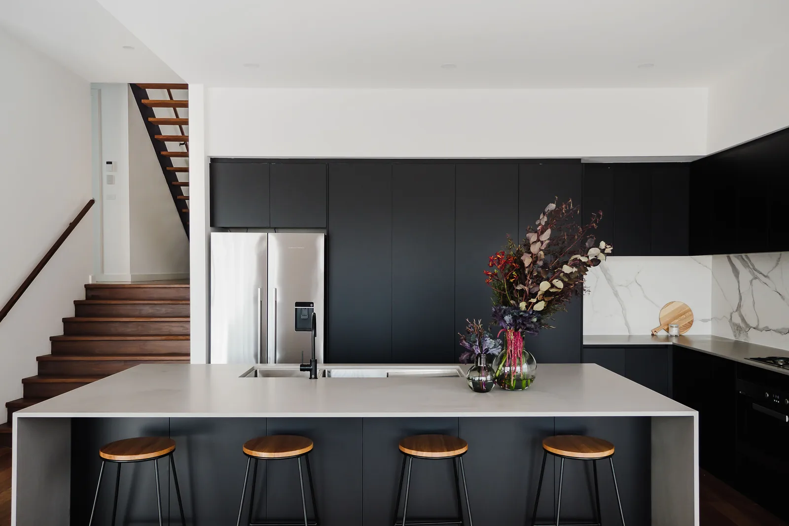Pale stone kitchen island with charcoal cabinetry and walnut floors