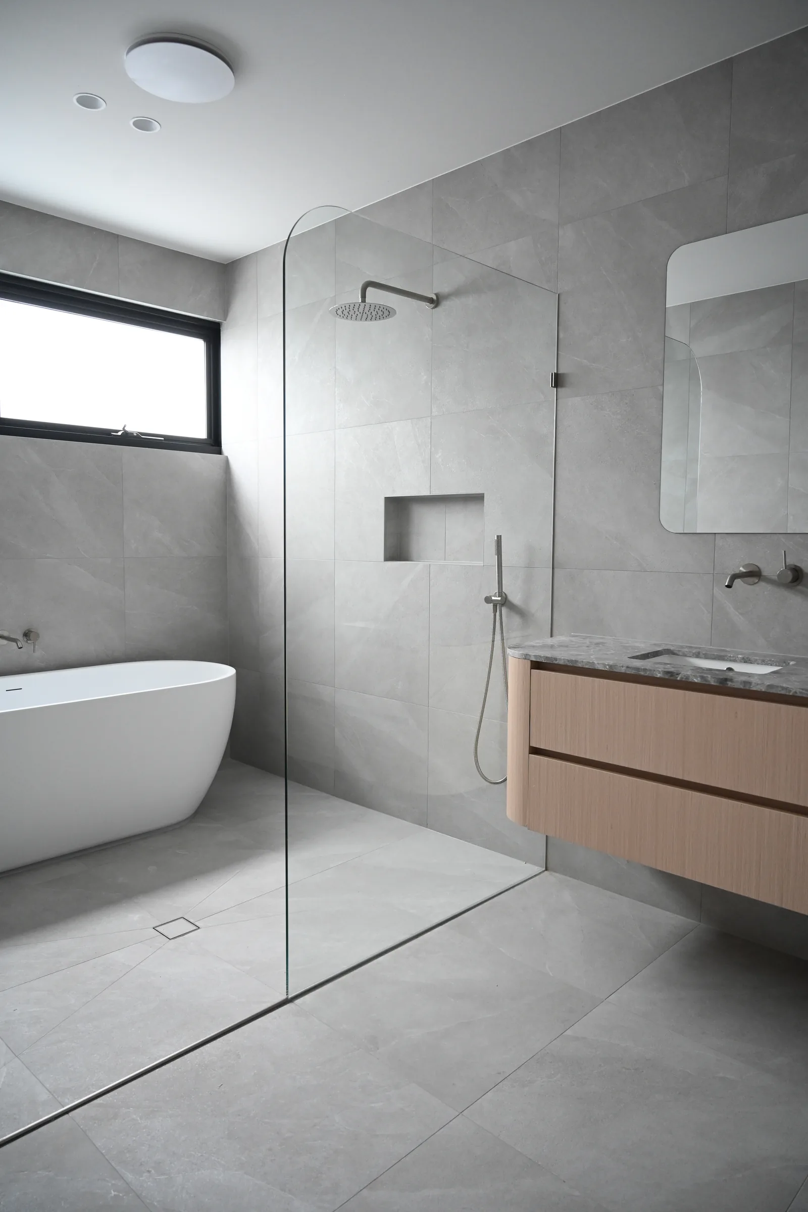 Bathroom at Noga Avenue with light tiles and a freestanding bath
